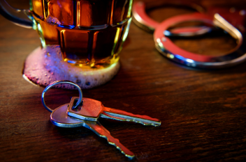 Glass of alcohol next to keys