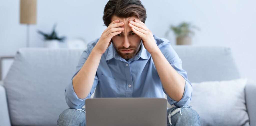 Stressed Businessman At Laptop Touching Head