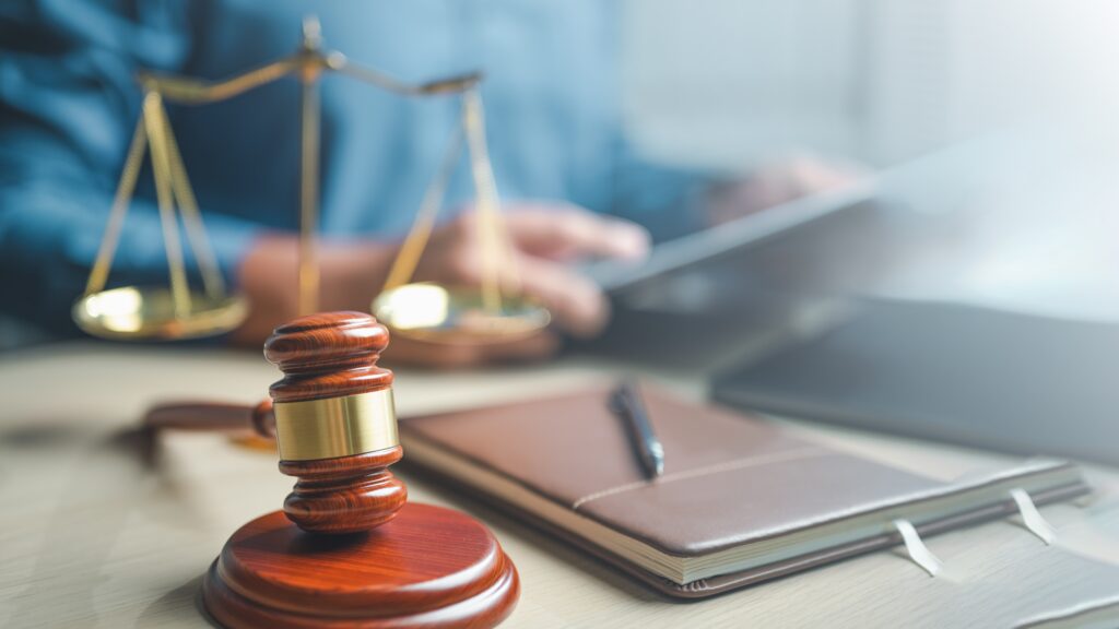A wooden gavel and justice scales on a lawyer’s desk