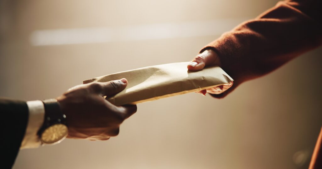 Hands passing envelope of cash